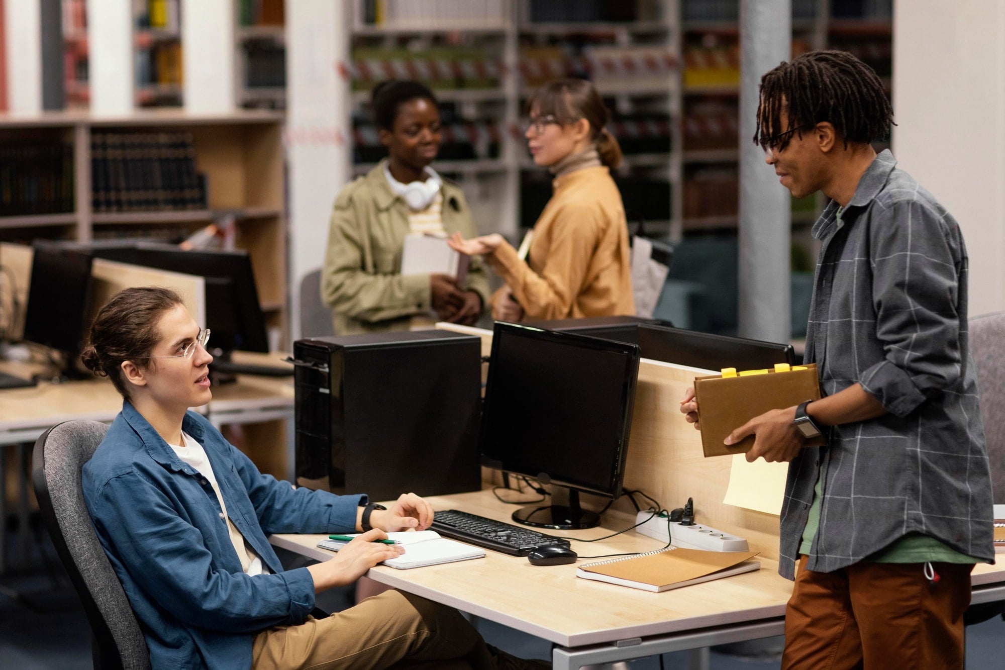 Two people talk at a desk with computers and books in a non profit organization in Minnesota with managed IT support.
